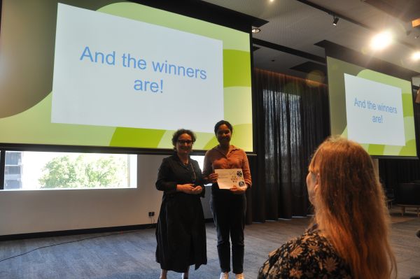 The Dean of Science presenting a certificate to a speaker in front of a slide reading 'And the winners are!'; one audience member is also visible