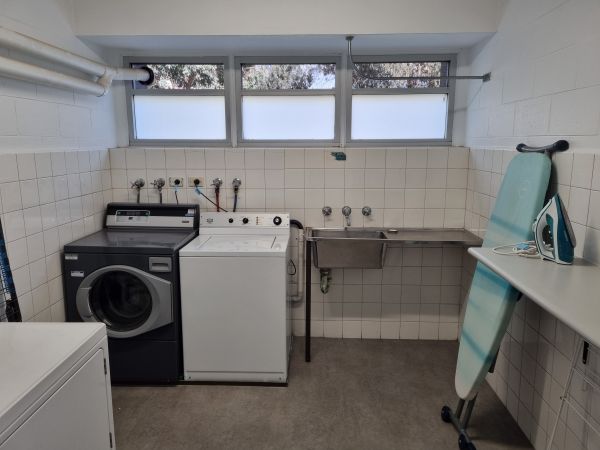 Laundry facilities showing washing machine, dryer, ironing board, sink.