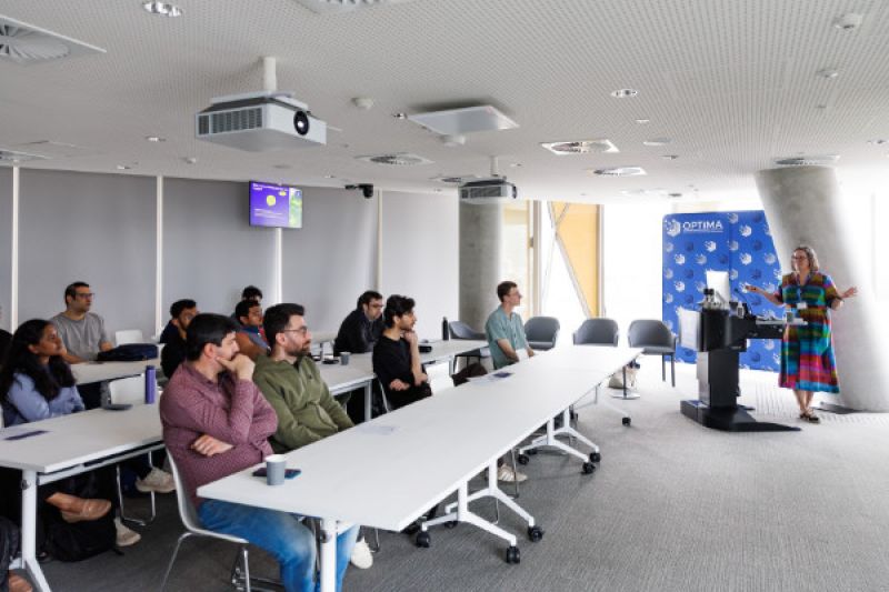 Woman presenting at lectern to a room of people sitting at desks.