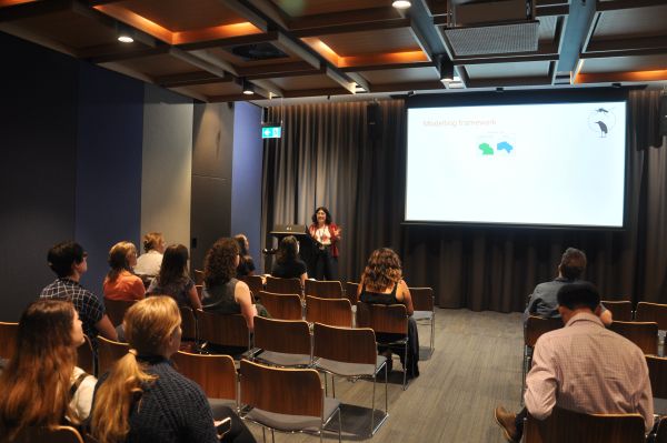 A speaker at the podium next to a slide titled 'Modelling framework'. Several rows of the audience can also be seen.