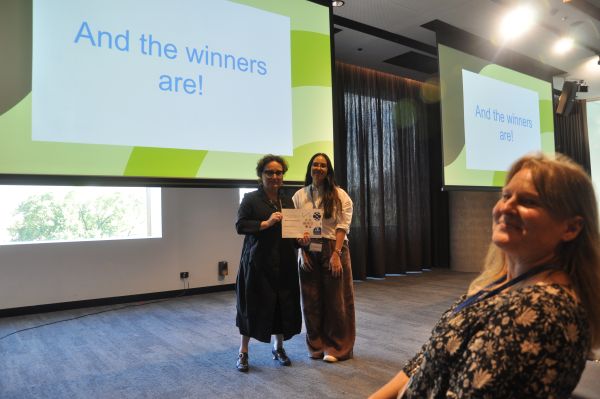 The Dean of Science presenting a certificate to a speaker in front of a slide reading 'And the winners are!'; one member of the audience is also visible