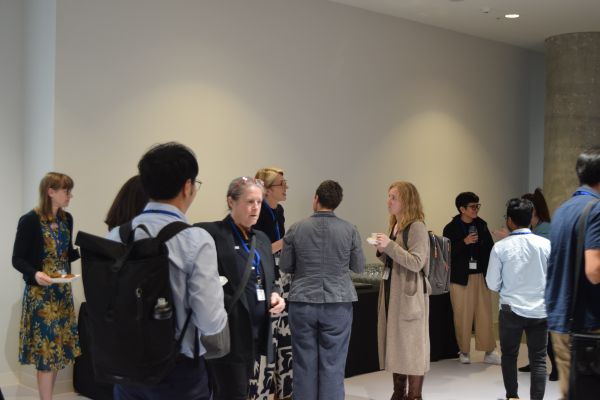 Around ten conference attendees talking in groups in the break area