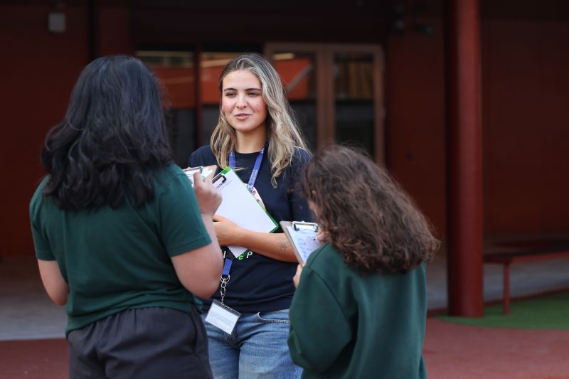 Female staff member talking to two primary school students
