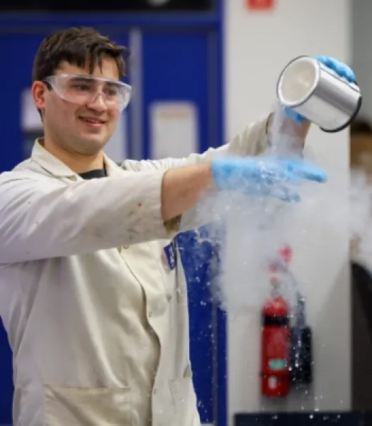 Man in lab coat pours dry ice on gloved hand