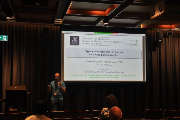 A speaker in front of a slide titled 'Typical entanglement for systems with fixed particle number'