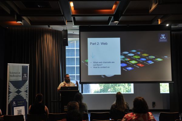 A speaker at the podium next to a slide titled 'Part 2: Web'