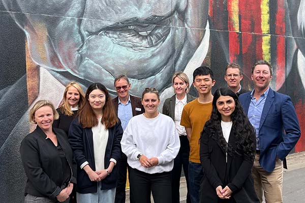 Norvicfoods students and staff standing in front of a mural