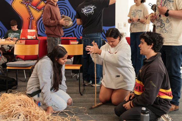 Two students try traditional fire starting with Wurundjeri people
