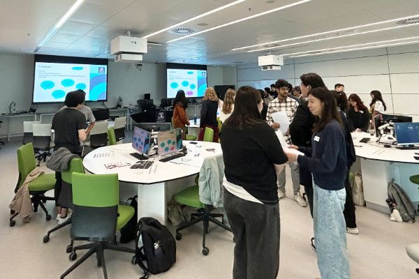 Students in a workshop standing among tables talking