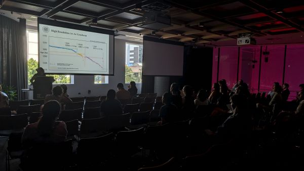 A speaker at a podium in front of a slide titled 'High-Resolution Ar-Ar Geochron'