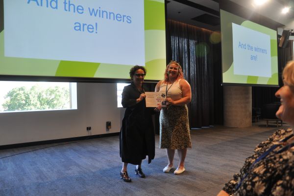The Dean of Science presenting a certificate to a speaker in front of a slide reading 'And the winners are!'; one member of the audience is also visible