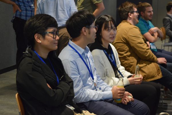 Audience members (seated and standing) talking; some are holding drinks