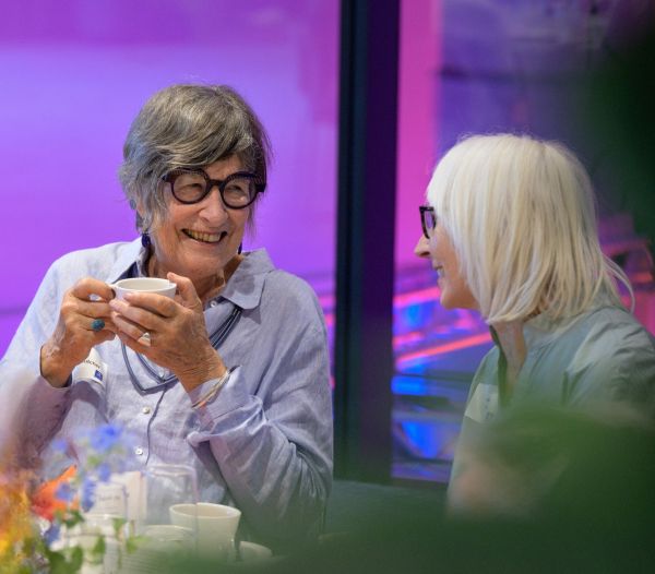 Two woman holding cups off coffee and talking with each other