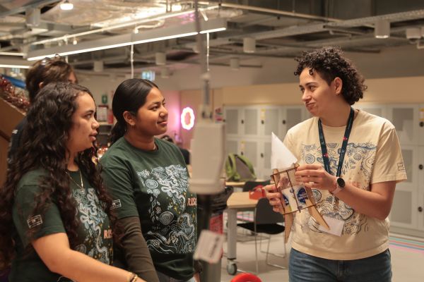 Two students and a mentor discuss their plastic bottle rocket design