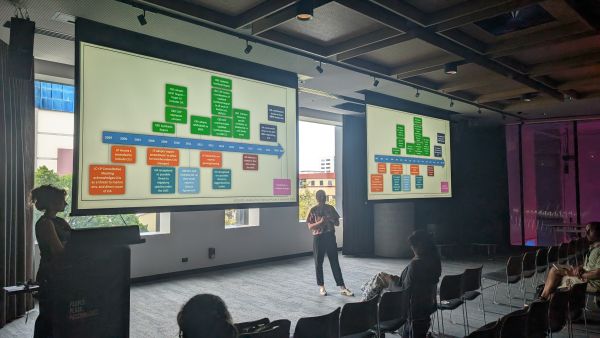 A speaker in front of slides showing a timeline