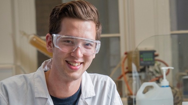 Image of James Ha looking at beaker in laboratory