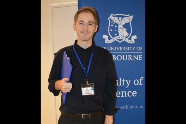 A conference organiser posing in front of a Faculty of Science banner