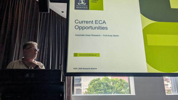 The Associate Dean (Research), Andy Martin, speaking from the podium - the talk title, 'Current ECA Opportunities', is visible on the slide