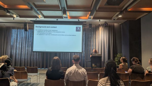 A speaker at a podium in front of a slide titled 'Background and context'