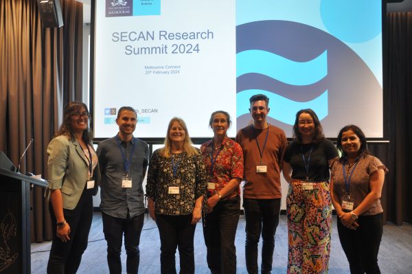 The conference organisers posing for the camera in front of a slide titled 'SECAN Research Summit 2024'