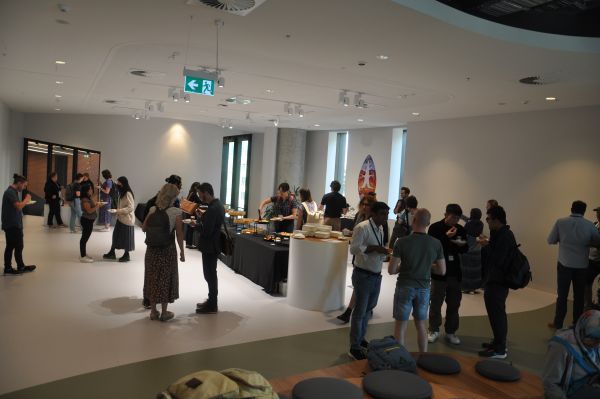 About twenty-five conference attendees talking and eating in the break area