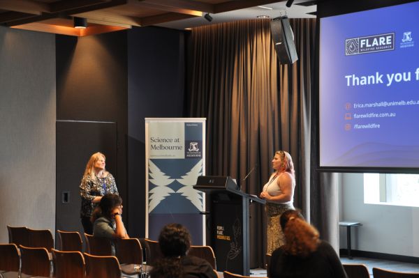 A speaker and session chair looking at one another, with part of the final presentation slide in frame