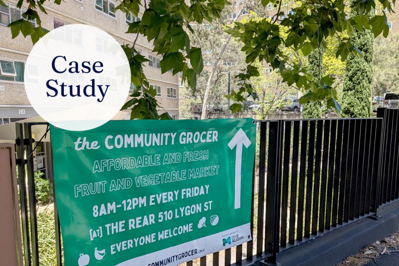 The Community Grocer signage on a fence at a market location