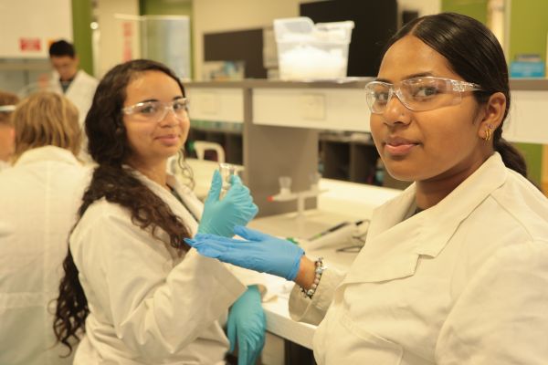 Two students wearing PPE conduct chemistry experiment