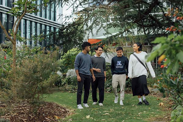Four students in conversation, standing in a campus garden