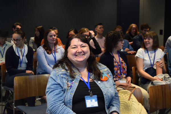 Seated members of the audience talking, one looking directly at the camera