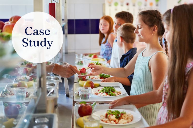 Children receiving healthy meals on their lunch trays at a school canteen. A white circle with the text 'case study' overlays the top left corner of the image