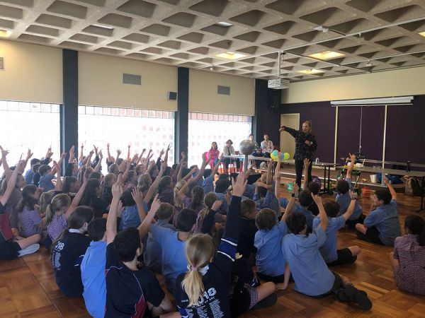 a primary school gym with many children sitting down inside